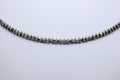 Necklace with blue and gold beads on a light gray background
