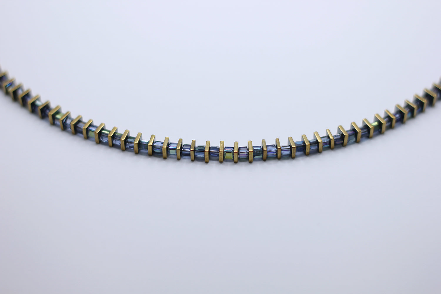 Necklace with blue and gold beads on a light gray background