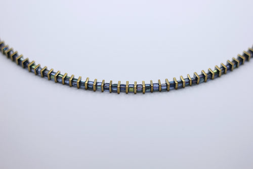 Necklace with blue and gold beads on a light gray background
