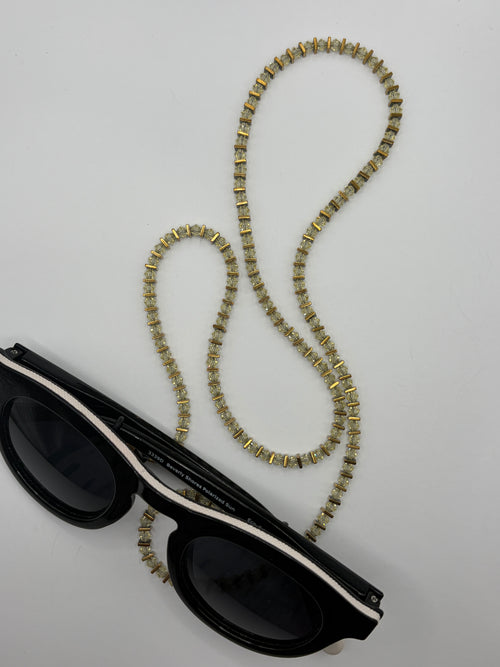 Black sunglasses with a decorative chain on a light gray background