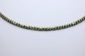Green beaded necklace on a light gray background