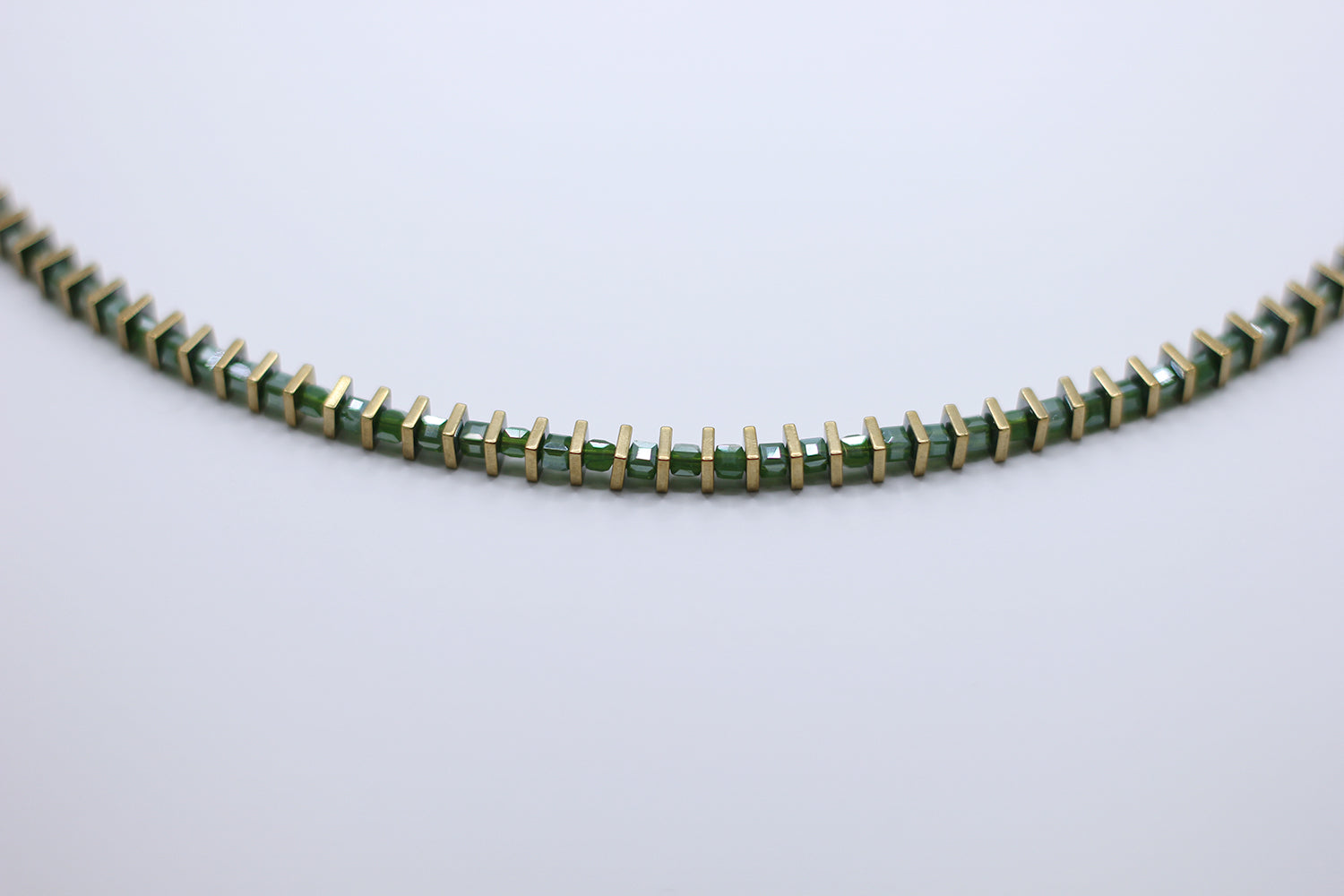 Green beaded necklace on a light gray background