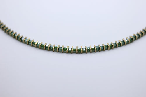 Green beaded necklace on a light gray background
