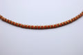 Necklace with orange beads and gold accents on a light gray background