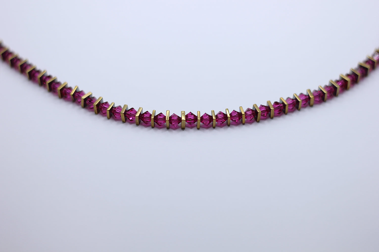 Necklace with magenta gemstones on a light gray background