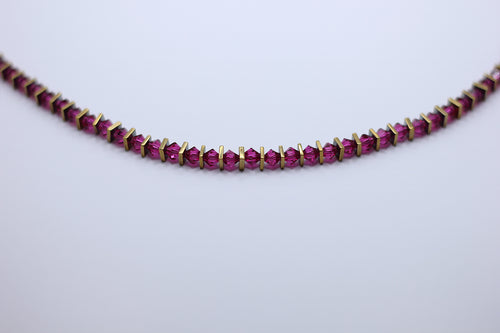 Necklace with magenta gemstones on a light gray background