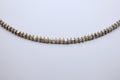 Necklace with gold and white beads on a light gray background