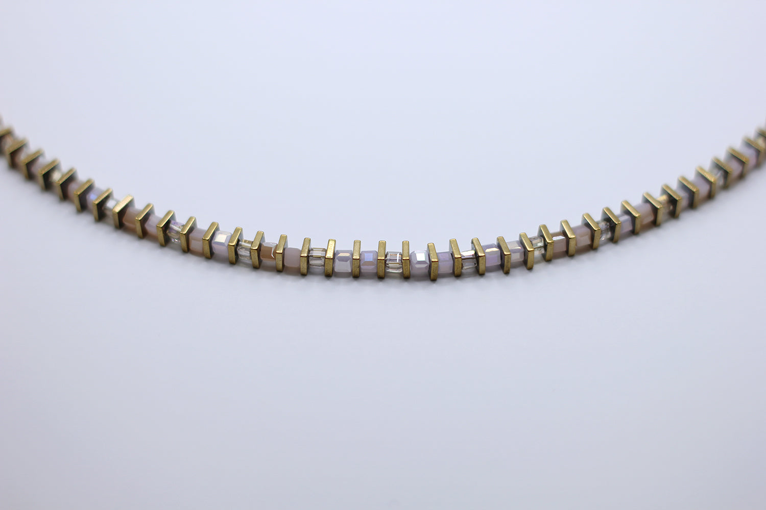 Necklace with gold and white beads on a light gray background