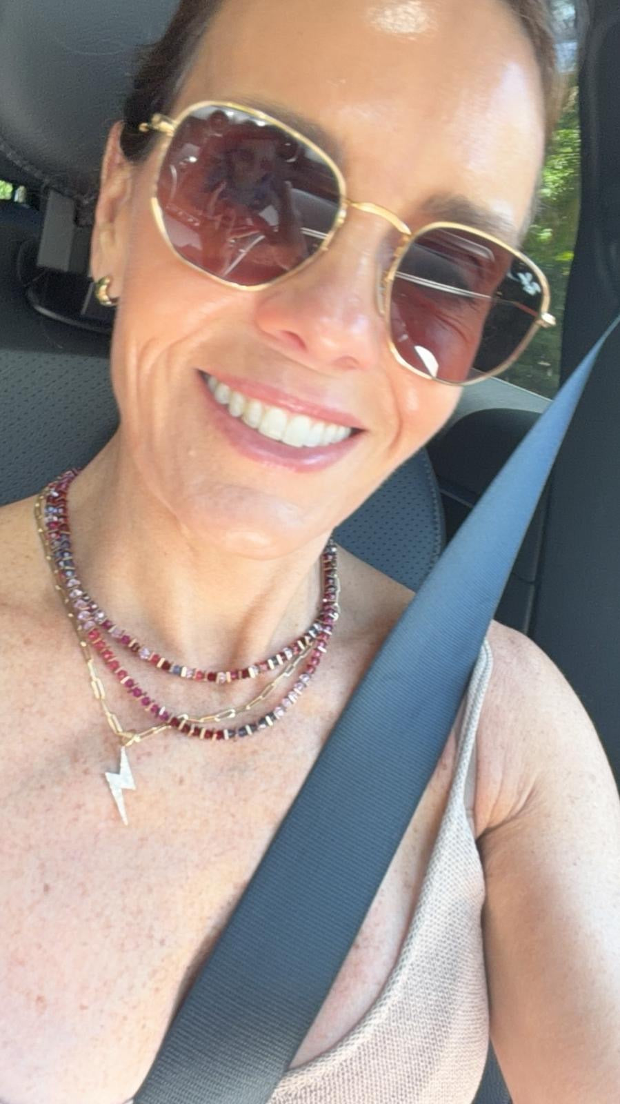 Woman wearing sunglasses and a seatbelt inside a vehicle
