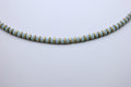 Necklace with light blue beads and gold accents on a light gray background