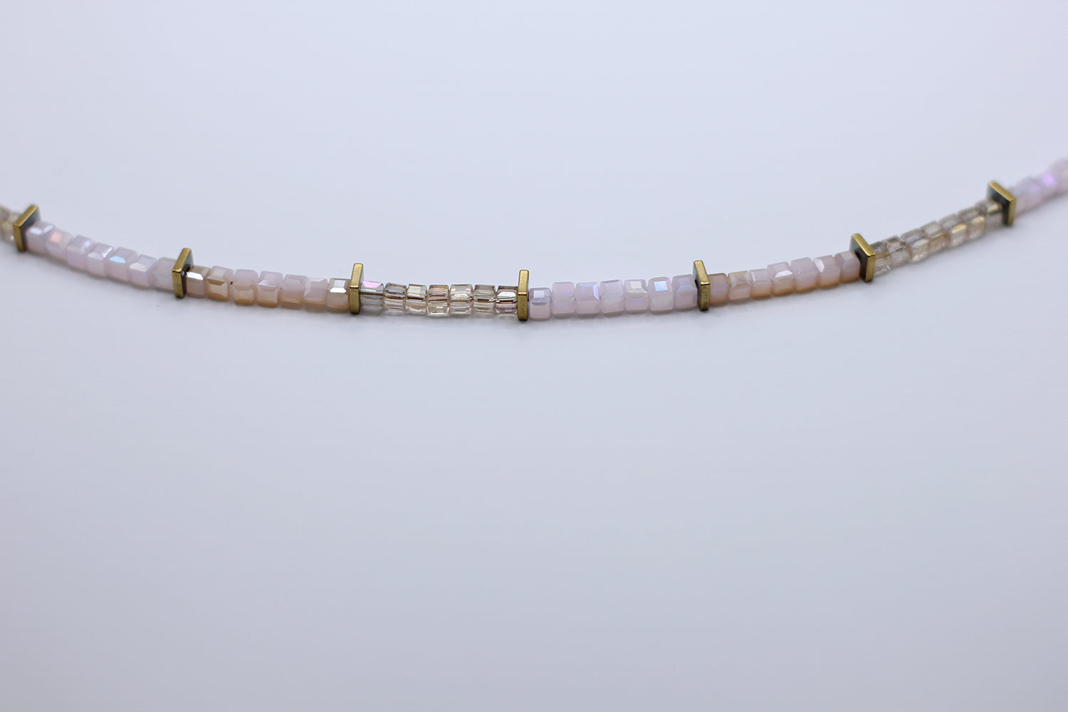 Necklace with pink beads and gold accents on a light gray background