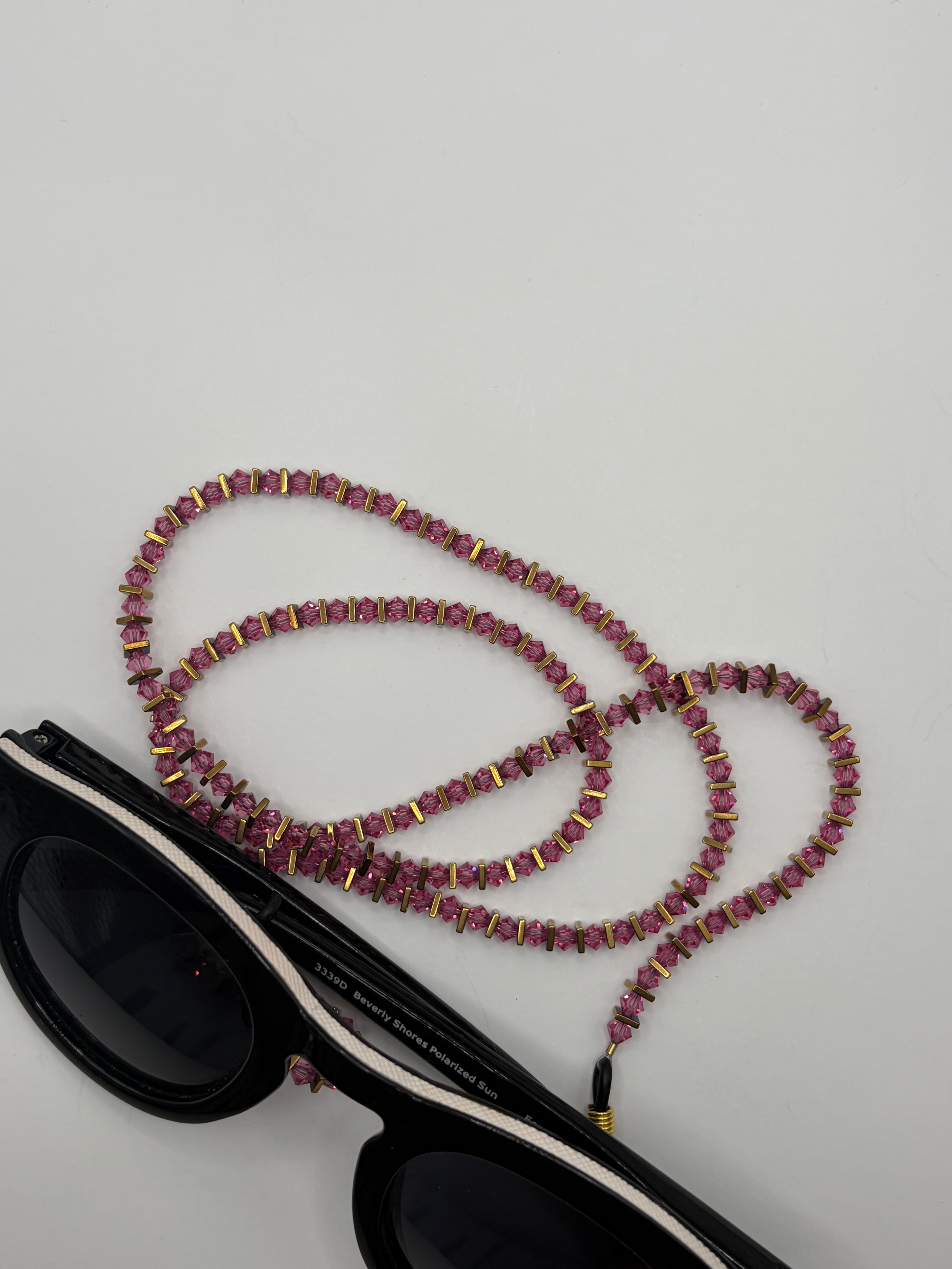 Sunglasses with a beaded lanyard on a light gray background