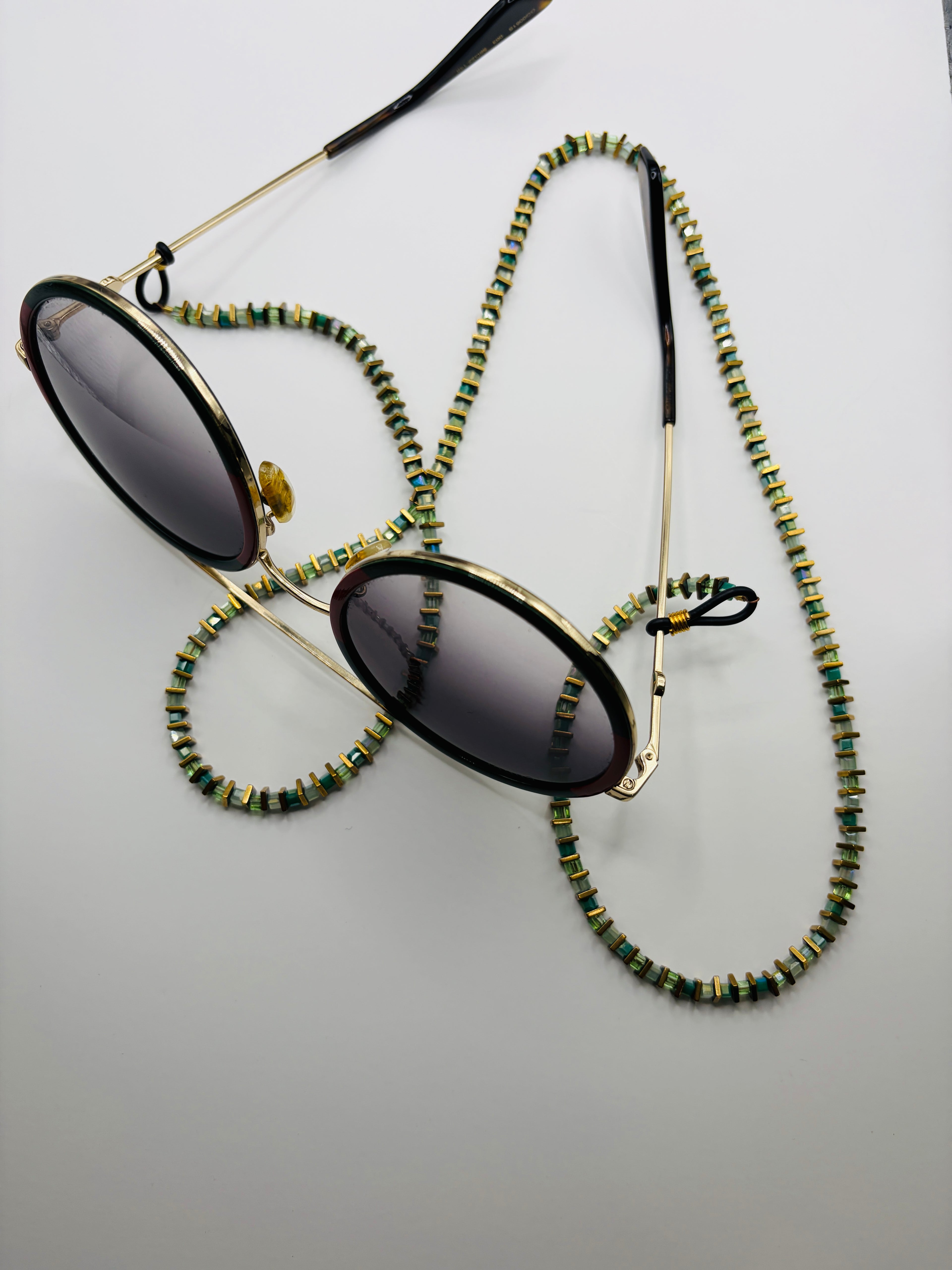 Sunglasses with a beaded chain on a light gray background