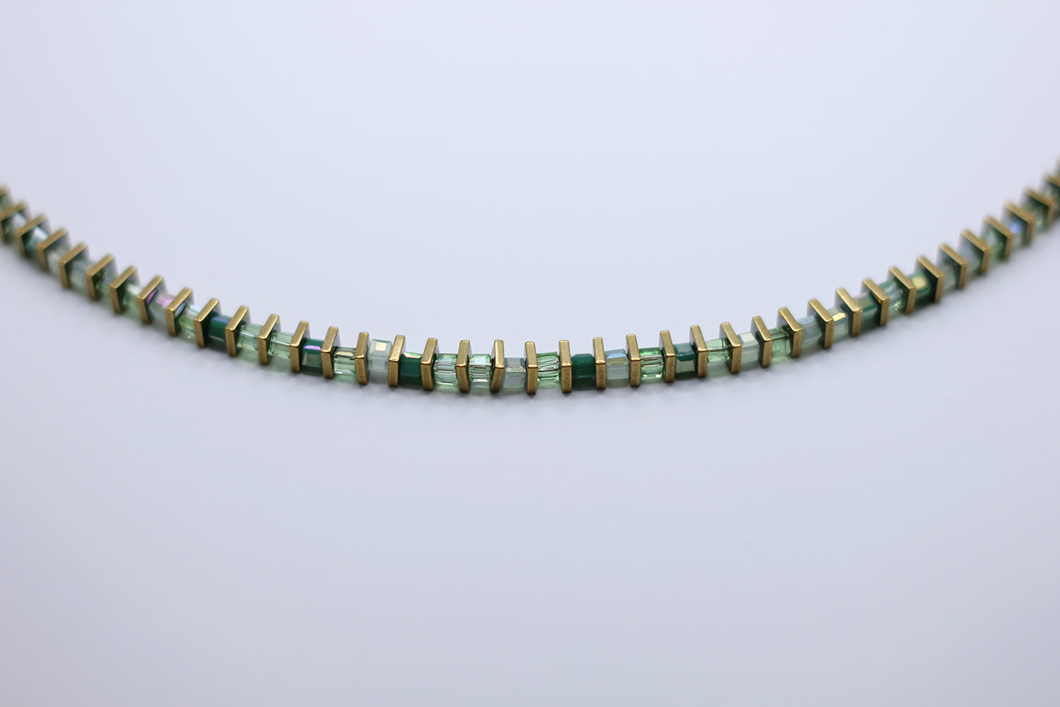 Necklace with green and gold beads on a light gray background