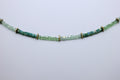 Green beaded necklace on a light gray background
