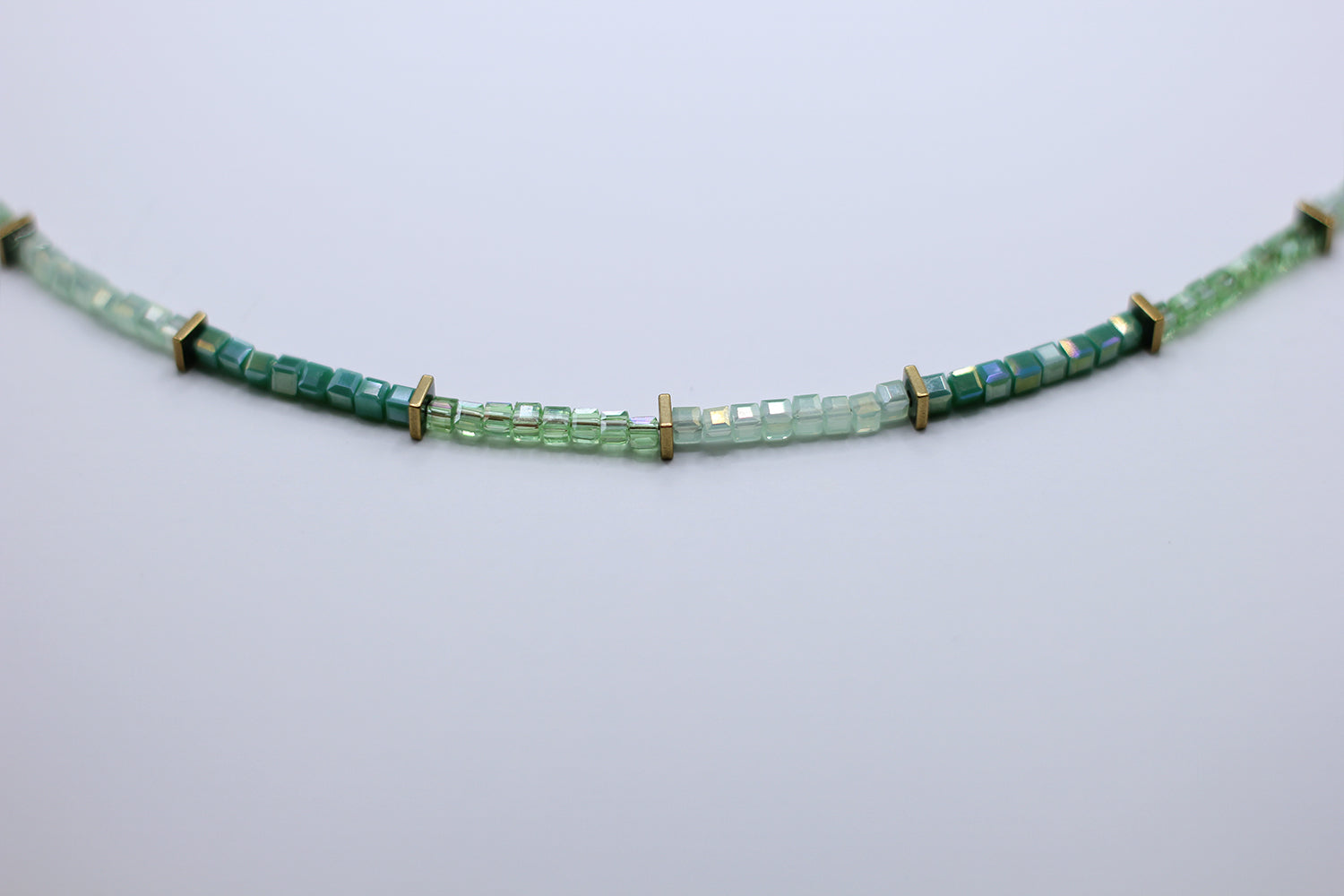 Green beaded necklace on a light gray background