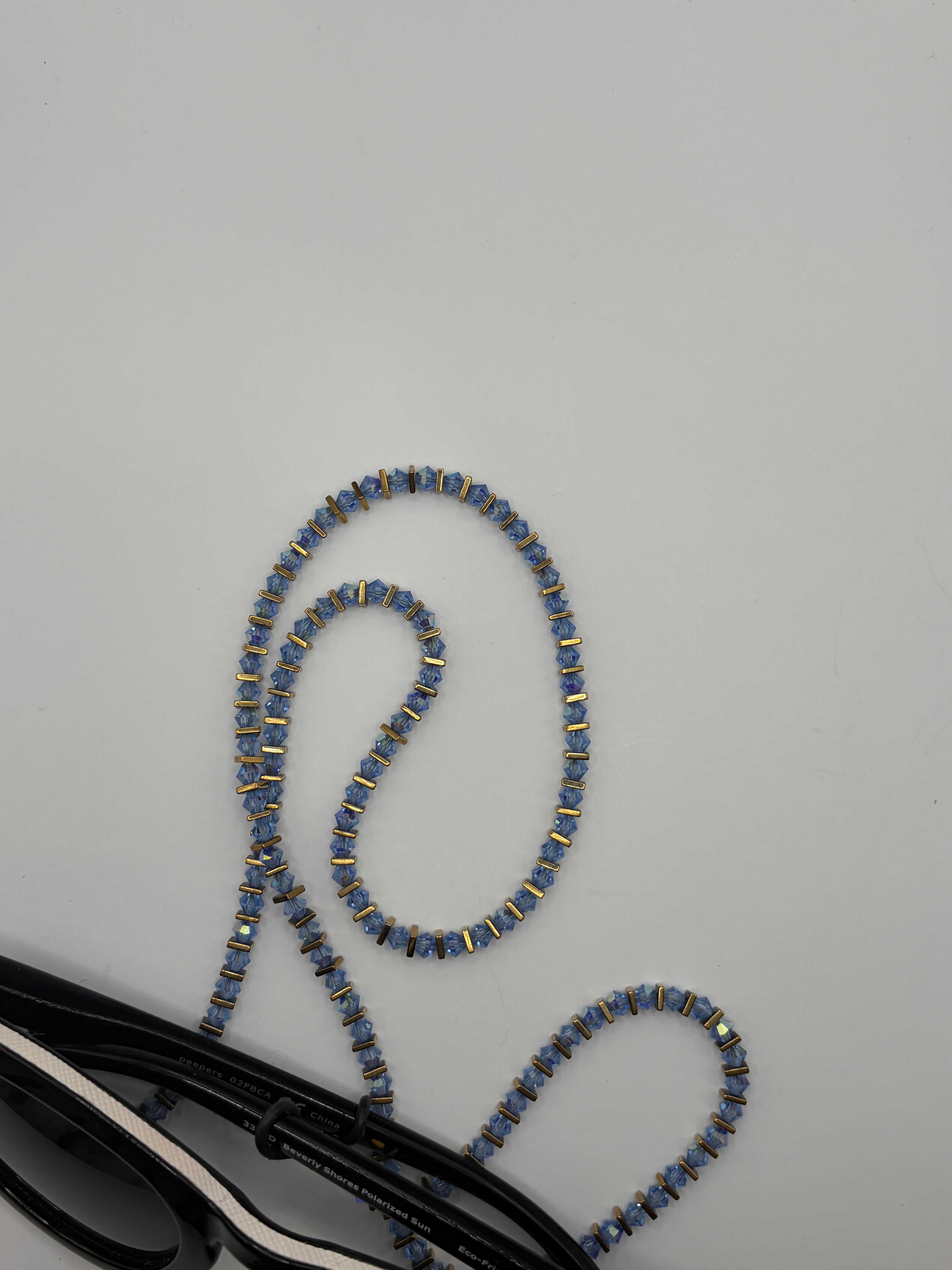 Blue beaded eyeglasses strap on a gray surface